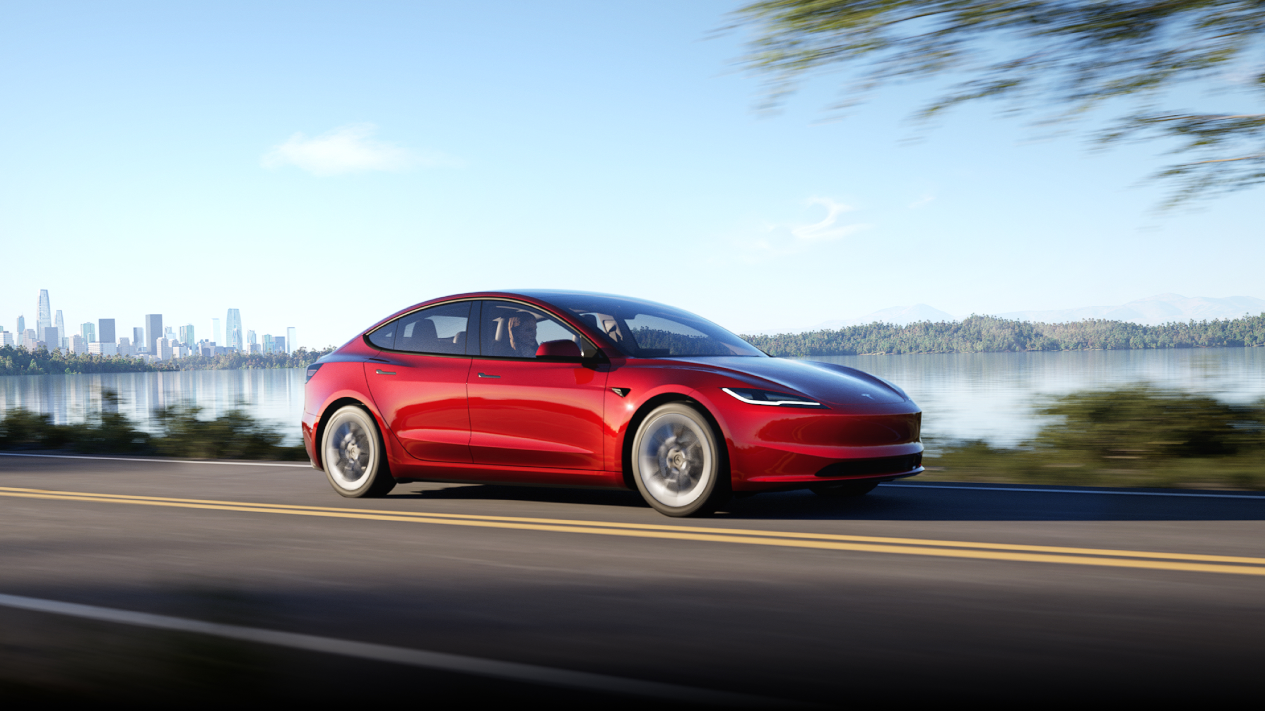 Ultra Red Model 3 roaming down a road with cityscape in the background.