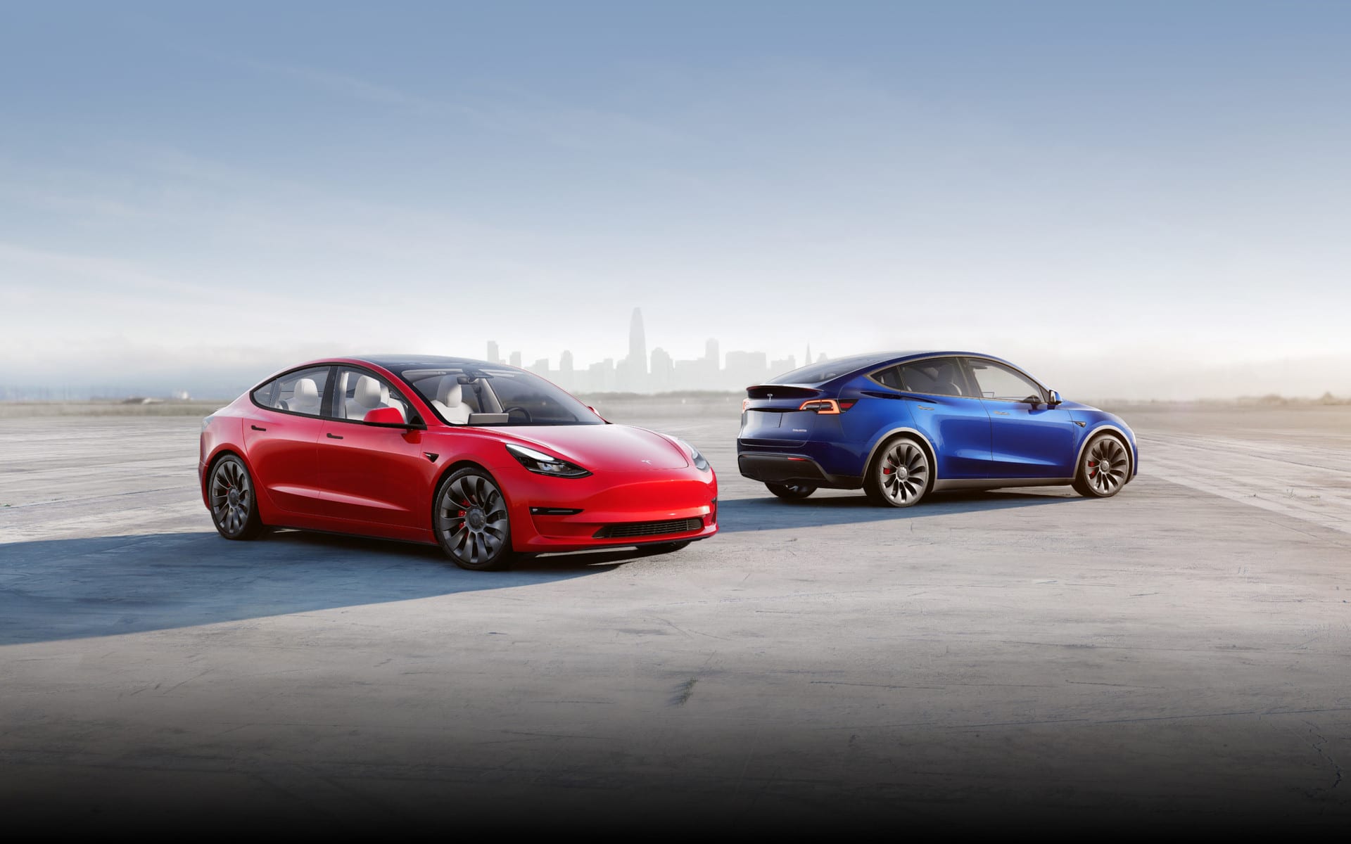 Une Tesla rouge et bleue garée devant un paysage urbain